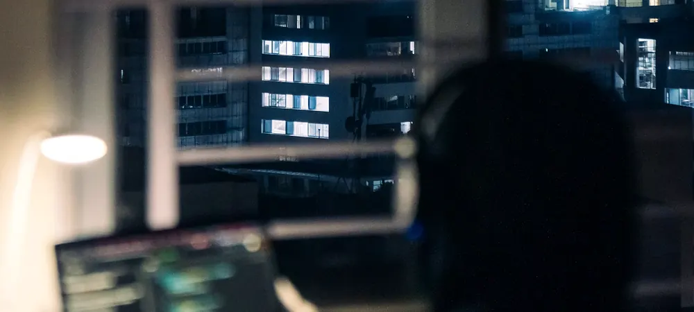 An engineer working late beside a window overlooking city offices