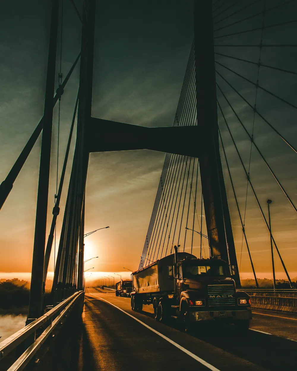 A truck crossing a cable-stayed bridge at sunrise